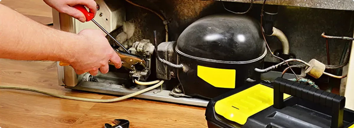 Refrigerator repair technician fixing the compressor and wiring in Morrison, CO