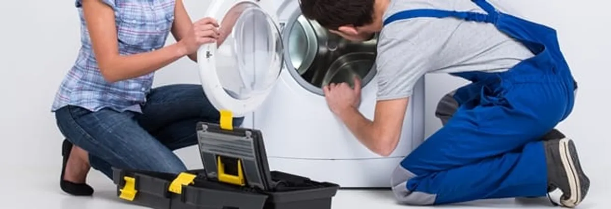 Washer repair technician inspecting a front-load washing machine with tools in Arvada, CO