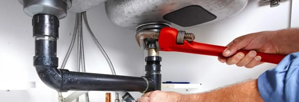 Garbage disposal repair technician tightening the sink drain and disposal connection in Arvada, CO