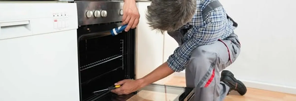 Oven repair technician inspecting and servicing an electric oven in Arvada, CO
