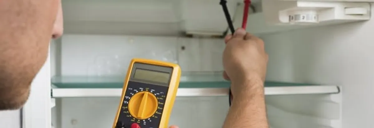 Refrigerator repair technician testing electrical components with a multimeter in Arvada, CO