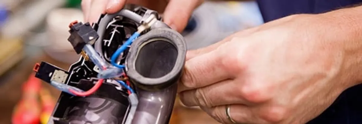 Vacuum repair technician reconnecting wiring and components in Arvada, CO