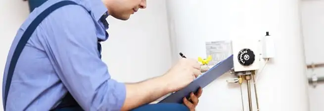 Water heater repair technician inspecting the unit and recording service notes in Arvada, CO