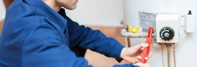 Water heater repair technician adjusting the temperature control and gas valve in Arvada, CO